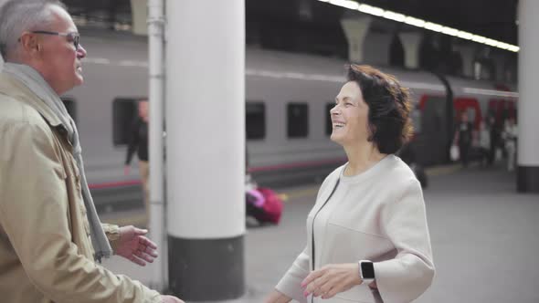 Happy Elderly Couple Hugging in a Train Station After Arrival