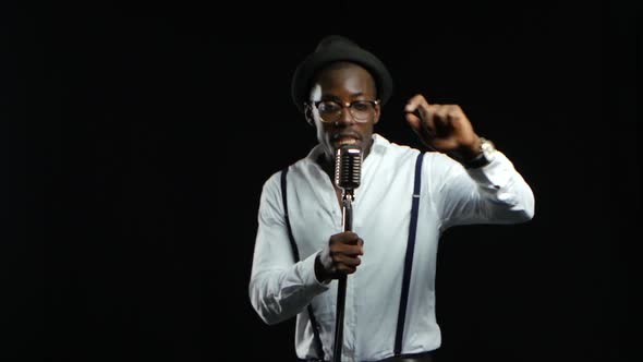 Singer Sings Into a Retro Microphone Spinning and Dancing Around Him. Black Background