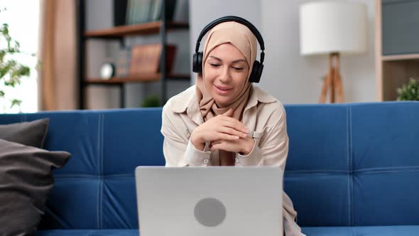 Young Muslim Woman Sit on Sofa in Living Room Study on Laptop  Arabic Girl Work on Computer