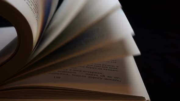 The Hand Turns Over The Pages Of The Book On Black Background