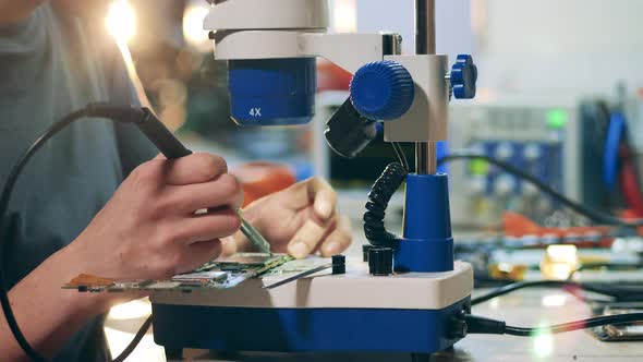 Circuit is Getting Soldered By a Repairman Using a Microscope