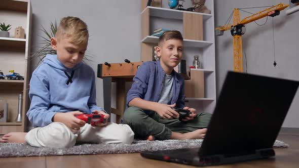 Teen Boys which Sitting on the Carpet and Emotionally Playing Video Game on Computer