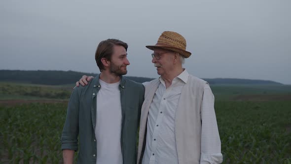 Two Men Stand on a Green Field and Talk