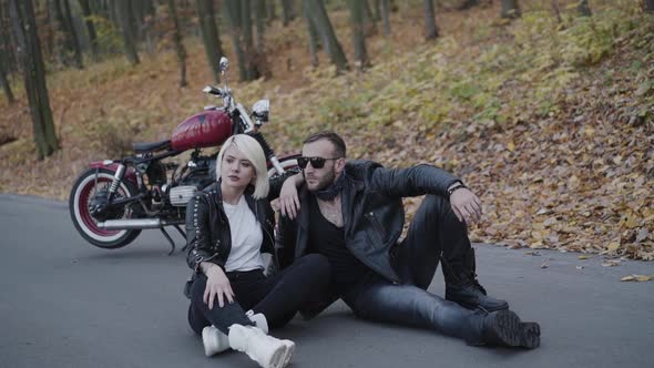 Portrait of Stylish Hipster Couple Sitting on Roadway in Pose