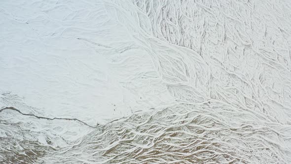 Drone Over Snow Covered Landscape With Frozen Braided Riverbed