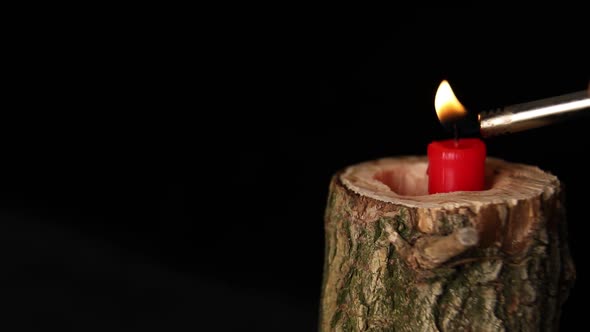 Man hand set on fire on candle in wooden candlestick black background