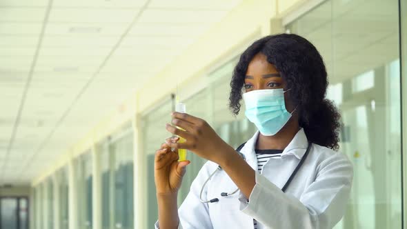 African American Doctor in Protective Mask Preparing Syringe for Injection. Close Up of African