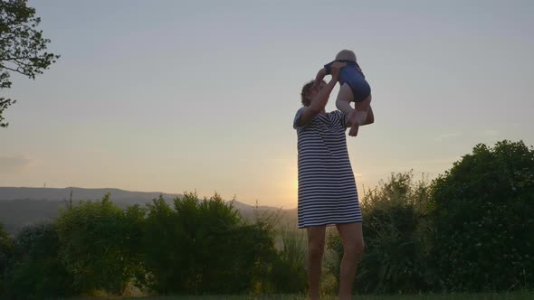 View of a Cheeful Mother Throwing and Catching Her Chubby Baby Into the Air