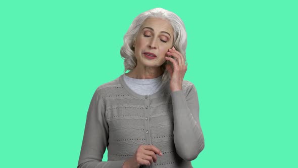 Senior Woman Talking on Transparent Phone on Color Background