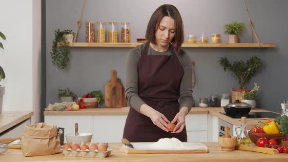 Woman Adding Egg to Flour while Cooking at Home