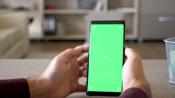 Close Up of Man Browsing the Internet on Smartphone with Green Screen Chroma Mock Up