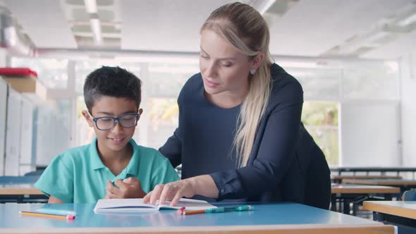 Friendly School Teacher Explaining Task To Pupil Boy