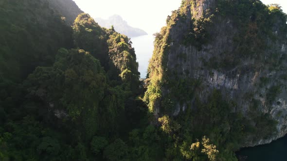 aerial drone flying between two limestone cliffs of Ko Poda Island with a secret white sand beach an