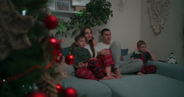 Family of Three  Father Mother and Tow Son Watching TV in the Evening