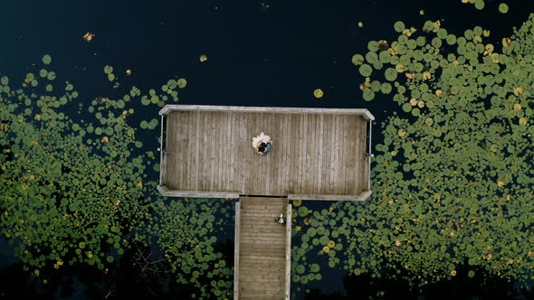 Bride and groom slow dancing on a dock on their wedding night surrounded by a pond filled with lily