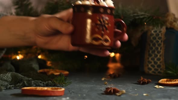 Hand Puts a Mug of Hot Chocolate with Marshmallow