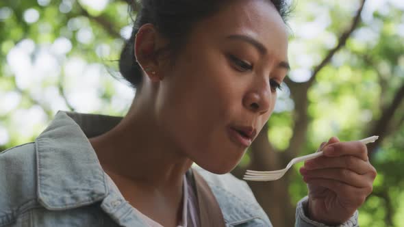 Mixed race woman eating on the street