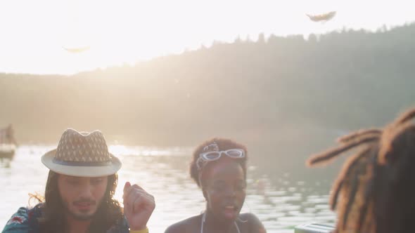 Company of Young Friends Toasting with Drinks at Lake Party