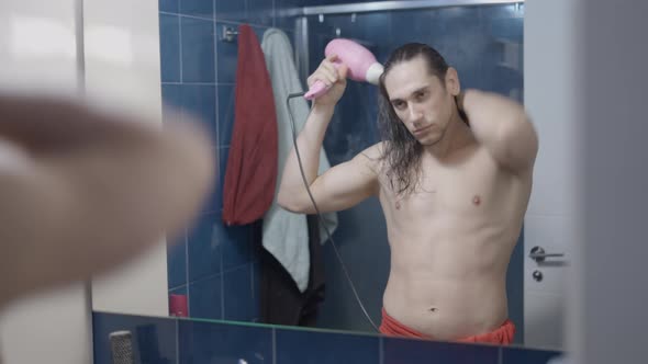 Young Metrosexual Man Using a Hair Dryer in Front of the Bathroom Mirror After a Shower  Time Lapse