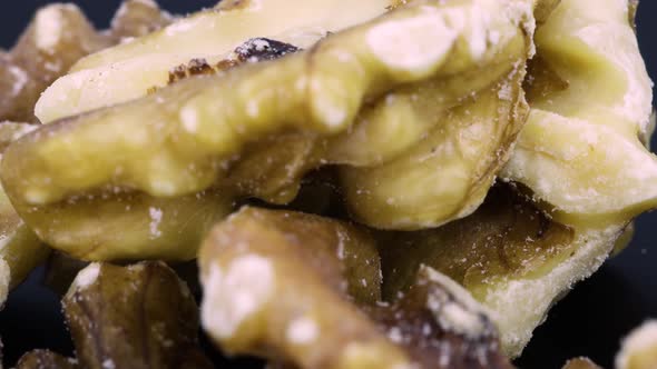 Close up shot, skin of peeled walnuts rotating over black surface background. Macro.