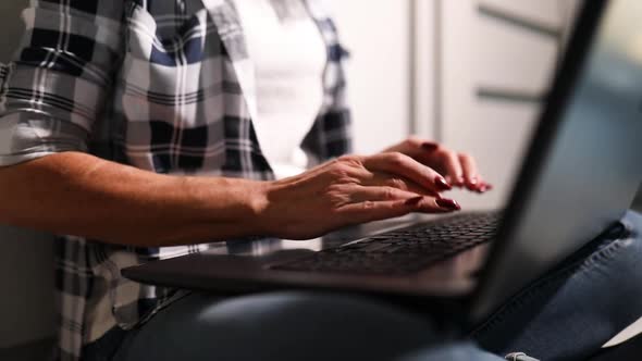 Senior mature woman using calculator on laptop, working from home