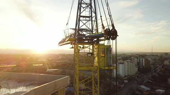 Aerial view of concrete frame of tall unfinished apartment building under construction in a city.