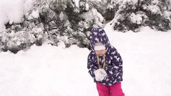 Child Plays Outside and Throws Snowballs