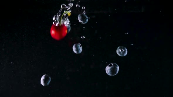 Blueberries and Cherries Fall Down Into Water with Bubbles