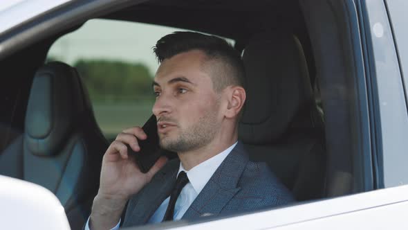 Young Businessman Talking On Mobile Phone In A Car