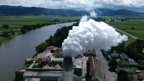 Smoke pouring out of a industrial smoke stack next to a river