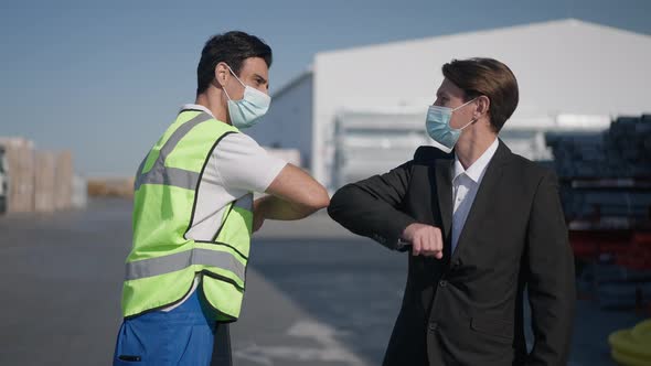 Medium Shot of Middle Eastern and Caucasian Men in Coronavirus Face Masks Touching Elbows Walking