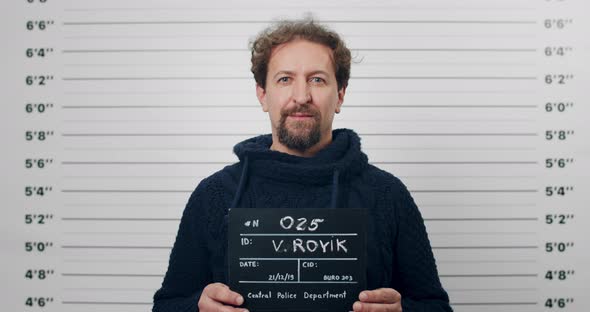 Portrait of Adult Bearded Man Holding Sign for Photo in Police Department