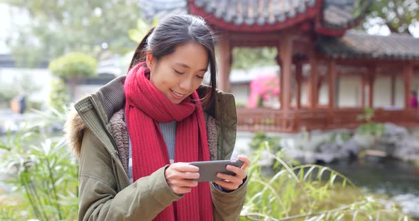 Young asian woman using smart phone in china, beautiful chinese pavilion garden