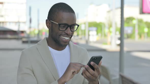 African Man Browsing Internet on Smartphone Outdoor