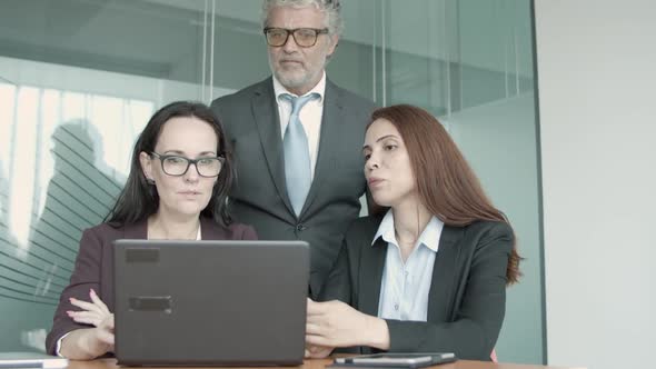 Three Caucasian Partners Discussing Project on Laptop