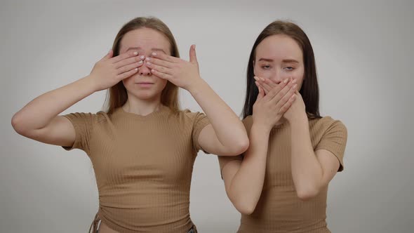 Twin Sisters Closing Eyes and Mouth Looking at Camera with Serious Facial Expression