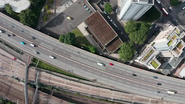 Top down drone shot of busy highway and train line surrounding residential area