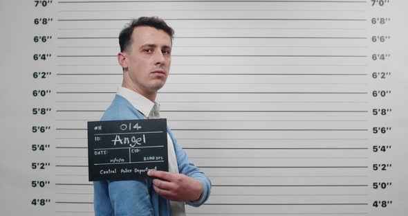 Mugshot of Criminal Man Turning Head and Looking to Camera While Standing Aside