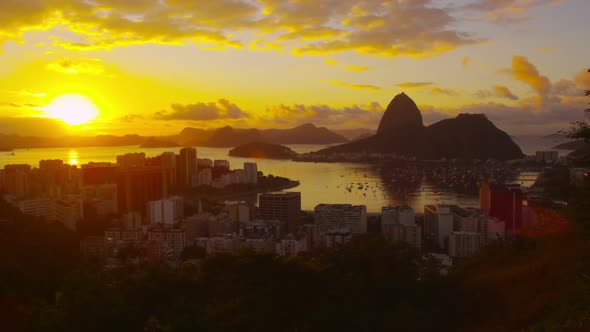 Lens flare and large setting sun tracking shot over Atlantic Ocean and Botafogo Bay.