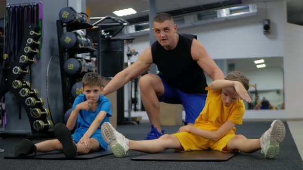 Coach Helps Children Perform Physical Exercises in Gym