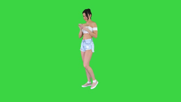 Cute Girl Checking Her Cell Phone and Dancing on a Green Screen, Chroma Key.