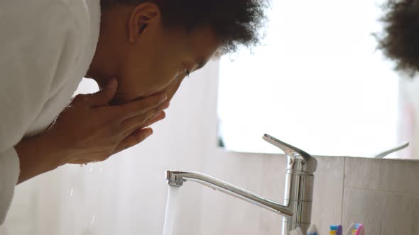 Close Up of African Man Washing Face in Bathroom Sink