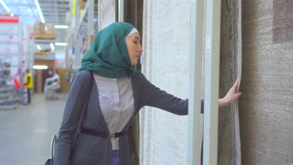 Young Muslim Woman Chooses a Carpet