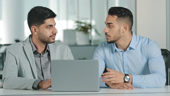 Two Indian Oriental Millennial Male Businessmen Looking at Laptop Screen Discussing Project