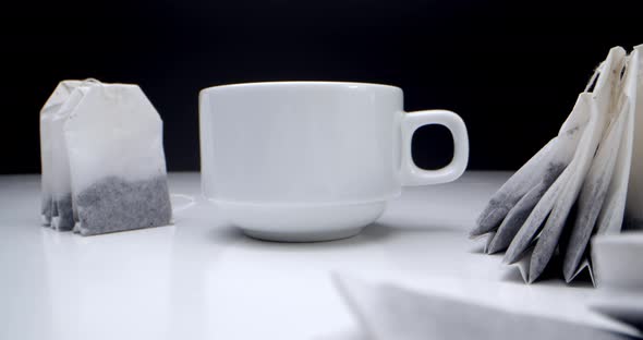 Super Closeup Set of Tea Bags on a White Table on a Black Background and a White Cup of Tea