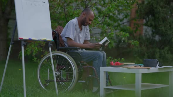 Side View Wide Shot Portrait of Desperate Depressed Disabled Man in Wheelchair Admiring Photo