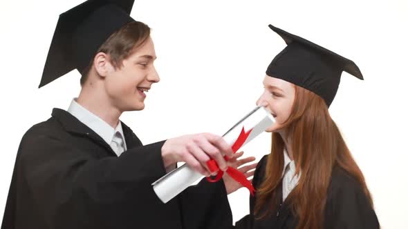 Two Happy Caucasian Boy and Girl in Black Robes and Square Academical Caps Hugging Each Other on