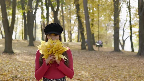 Happy Girl Sniffing Maple Leaves Bouquet Throwing It Up and Laughing at Camera