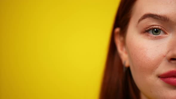 Half Face of Smiling Young Redhead Woman on the Right at Yellow Background