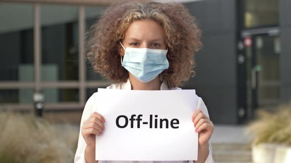 Schoolgirl Wearing a Medical Mask Holds a Sign OFFLINE